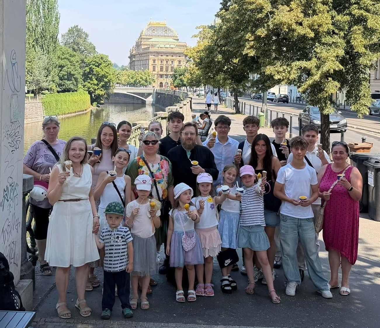 Skupina se zmrzlinou u Vltavy s Národním divadlem v pozadí